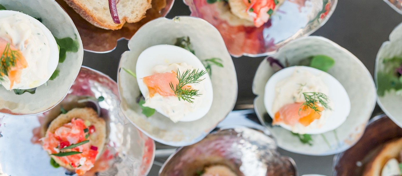 An assortment of elegant canapés: crostini, deviled eggs with herbs, smoked salmon bites, and fresh toppings on stylish glassware, vibrant and bite-sized.