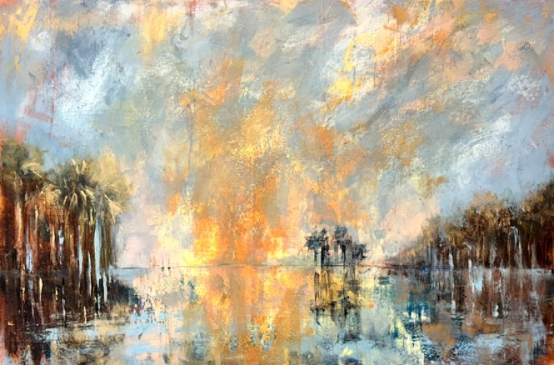 Sunset over a water scene with palm trees along a calm shore, reflected clouds and warm golden light spilling across the sky.