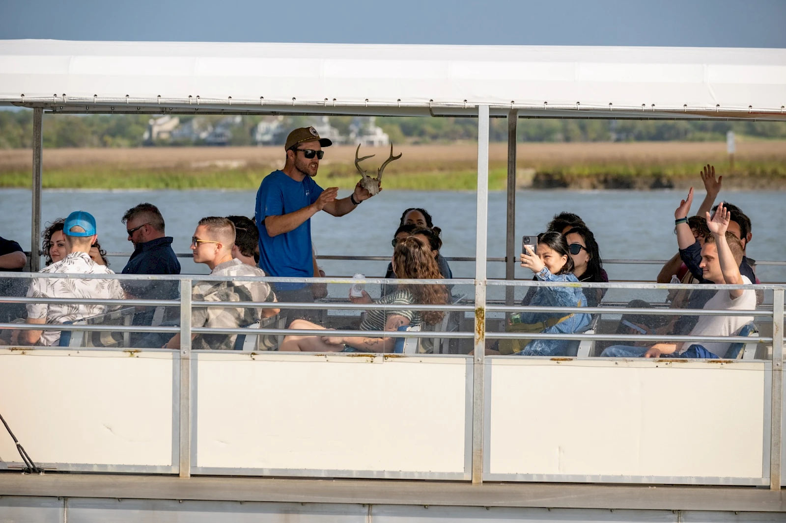 Guide holds deer antlers while speaking to guests on a Lowcountry wildlife boat tour.