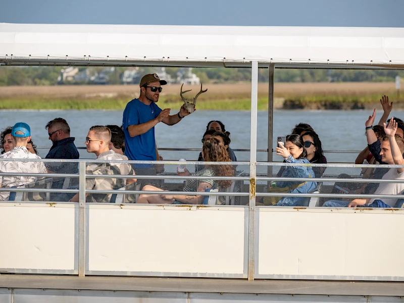 Guide holds deer antlers while speaking to guests on a Lowcountry wildlife boat tour.