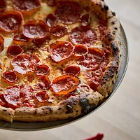 A pepperoni pizza on a round tray, crusty edges, melted cheese, and pepperoni slices baked to perfection.