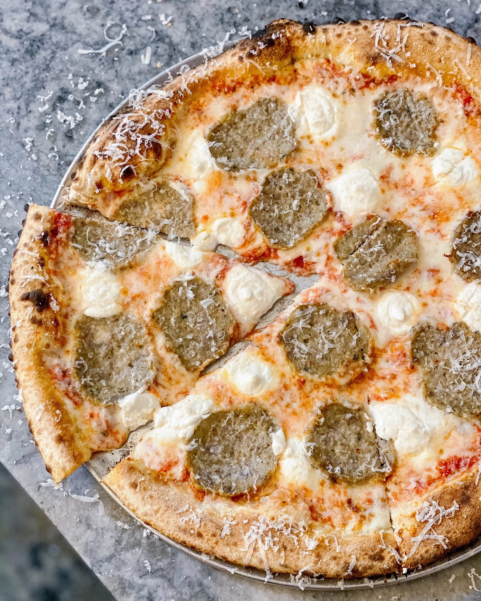 Whole pepperoni and cheese pizza, sliced, cooling on a rustic surface, with a golden crust and bubbling mozzarella.