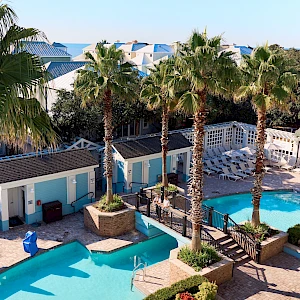 A sunny resort scene with blue pool, palm trees, white railings, and lounge areas around turquoise water, perfection for a tropical getaway.