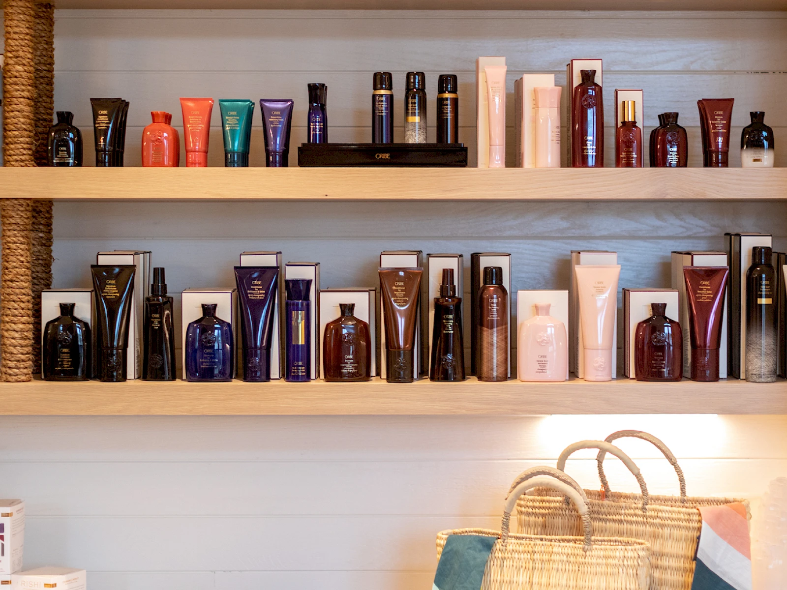 Shelves with grooming products and bags on a counter; various bottles, boxed items, and a woven tote bag with a striped cloth nearby.