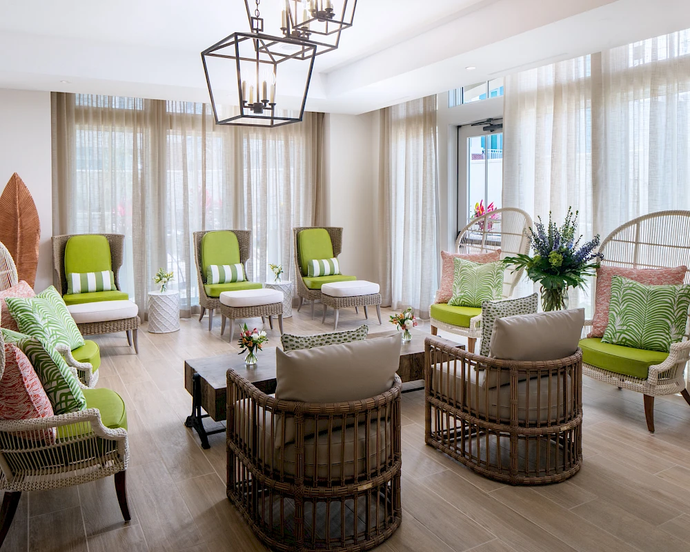 A bright, airy lounge with wicker chairs, lime cushions, pastel pillows, and sheer curtains; a cozy circle for conversation and relaxation.