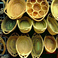 Handwoven bamboo baskets for sale, oval and round, natural tan color, intricate weave patterns, stacked on shelves for display.