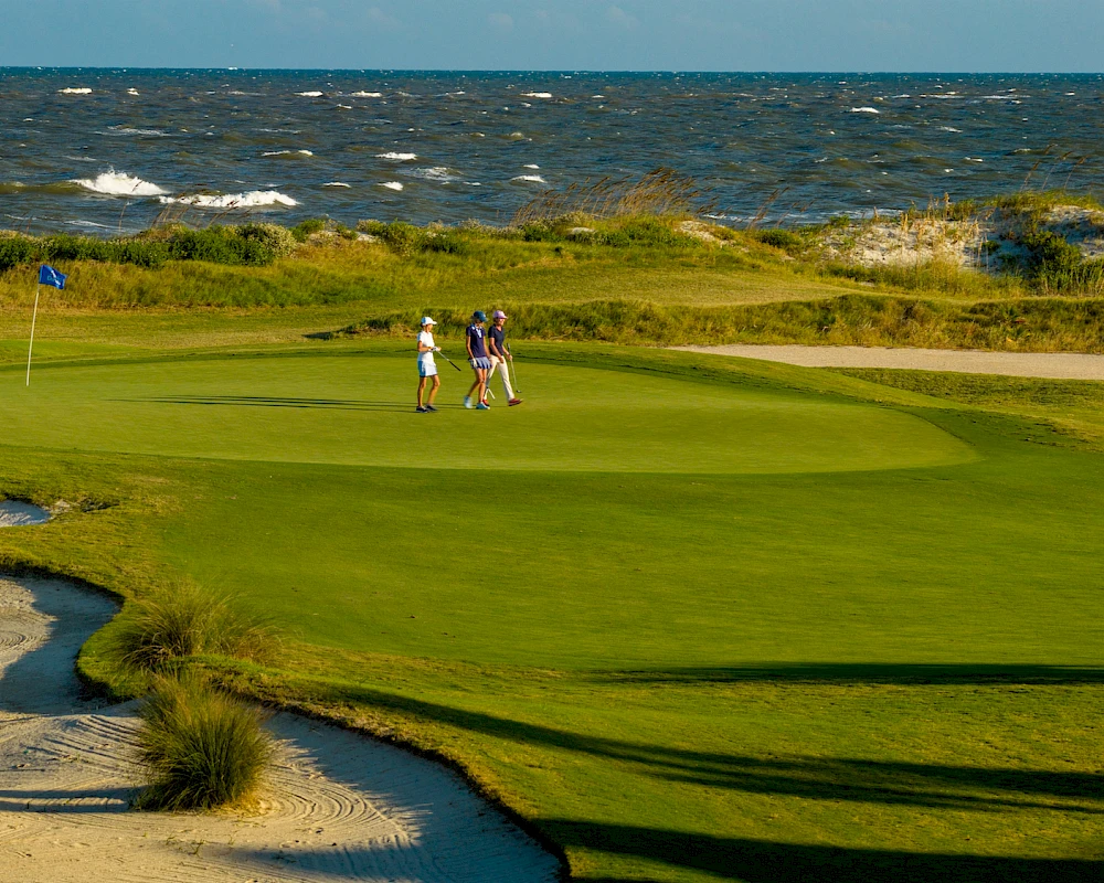 Two golfers on a seaside golf course, green near the shore, sand traps, waves in the background, calm sunny day.