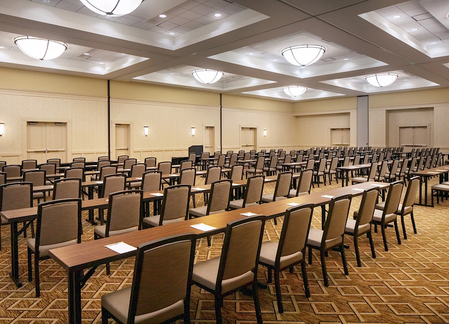 A large conference room set up with many rows of chairs and long tables, arranged theater-style for a presentation or meeting, neutral lighting.