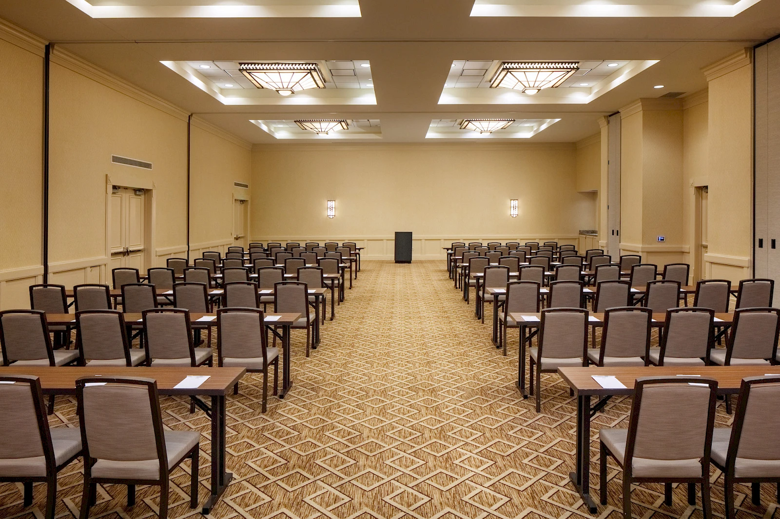 A large conference room set up with rows of chairs and desks facing a podium at the front, ready for a seminar or meeting.