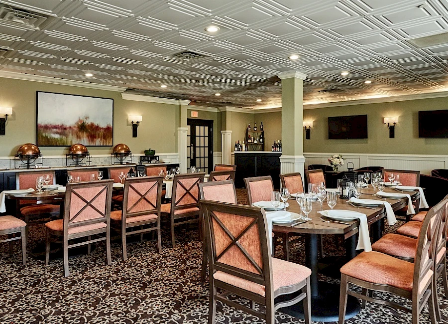 A formal dining room with wood chairs, pinkish cushions, arranged tables, place settings, and soft wall lighting—elegant and inviting.