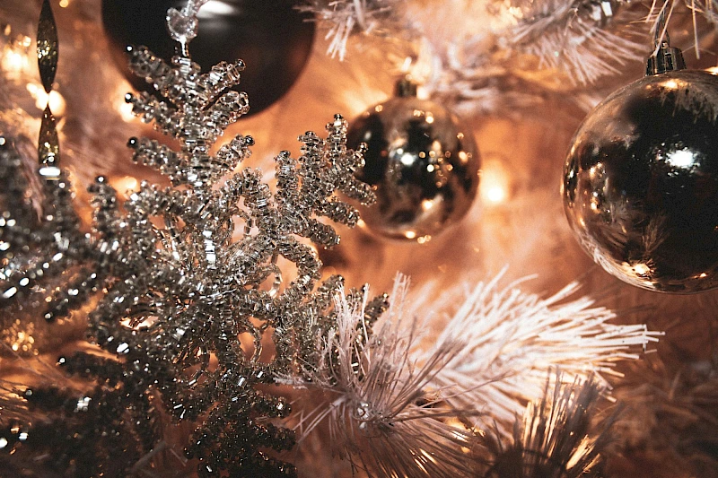 Sparkling silver and white Christmas decorations on a tree, with glittery frosted branches and shiny ornaments, warm festive lights, and a cozy glow.