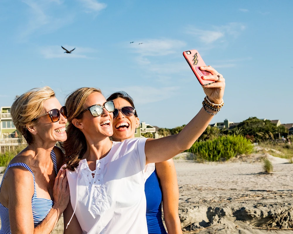 Three women taking a selfie on Wild Dunes beach.