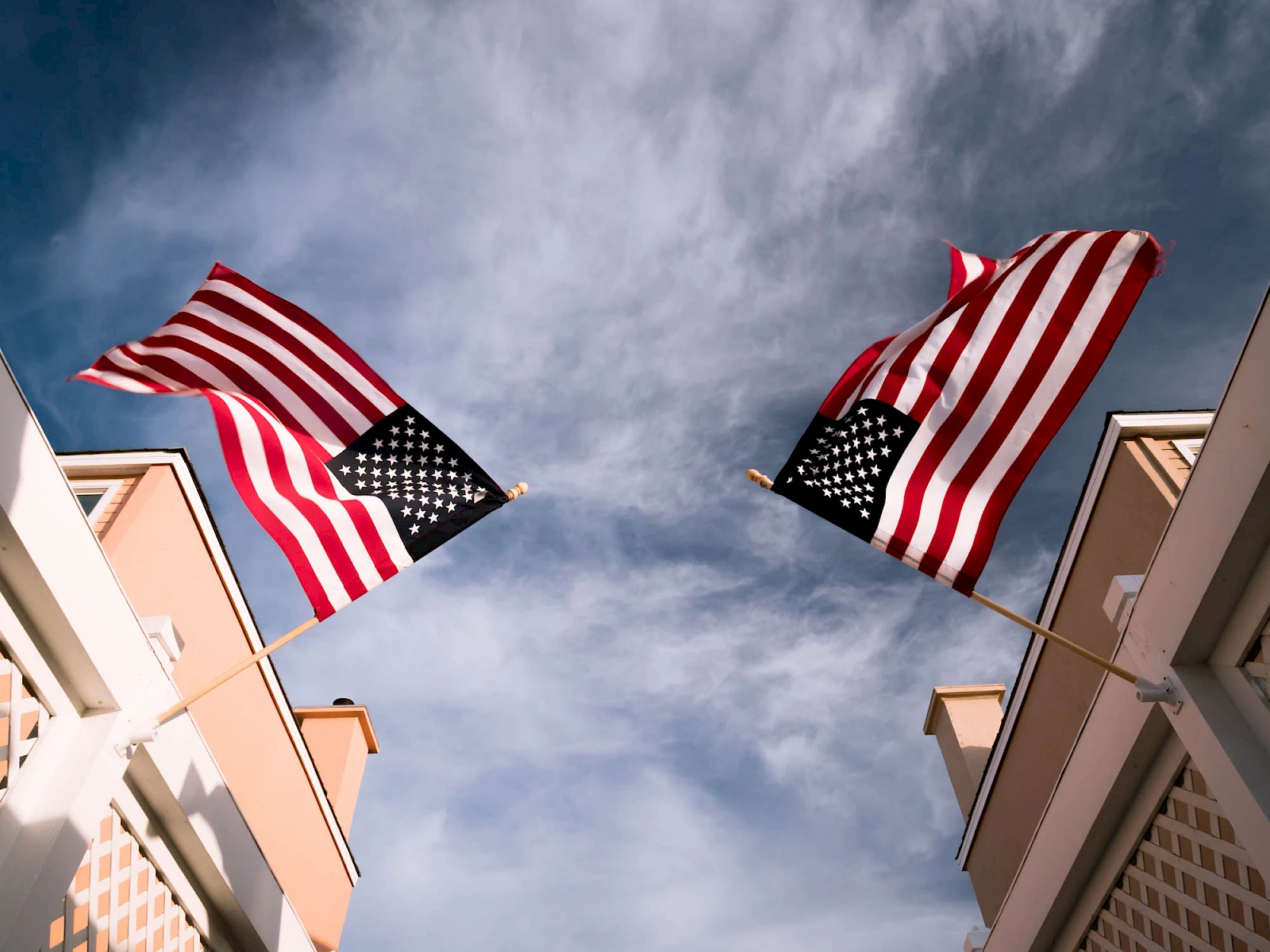 Two American flags waving above buildings against a blue sky, creating a patriotic urban scene.