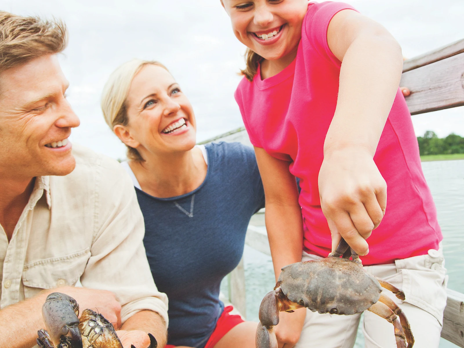 Shark? No—crabs! A family releases small crabs from a yellow crate by the water, smiling as they handle them carefully. (140 chars, ends with a period.)