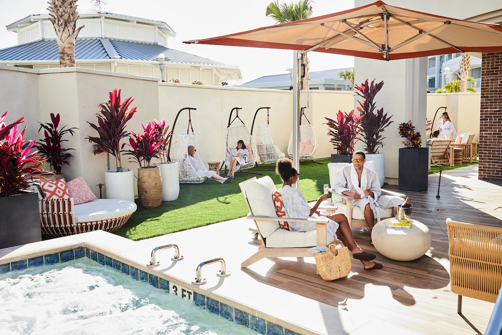 A sunny rooftop poolside lounge with cabanas, frou-frou chairs, a large umbrella, and guests relaxing near the water. Top it at 140 characters, always ending the sentence.
