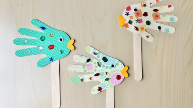 Colorful DIY hand puppets on popsicle sticks—blue and white polka dots with yellow mouths, and a rainbow-speckled dream hand, cutouts galore.